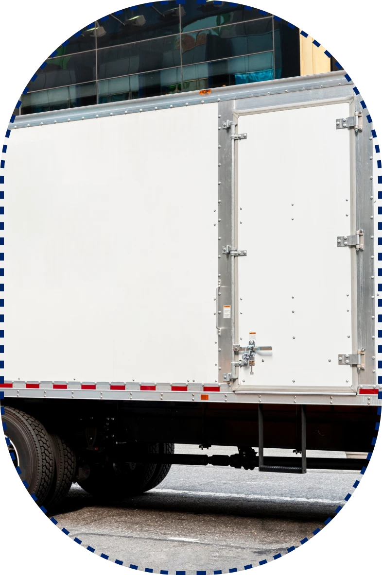 A white delivery truck with a clean side panel, closed rear door, black wheels, and reflective stripes on a street.